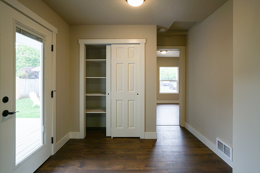 Photo of French door leading to back yard and open closet near the door.