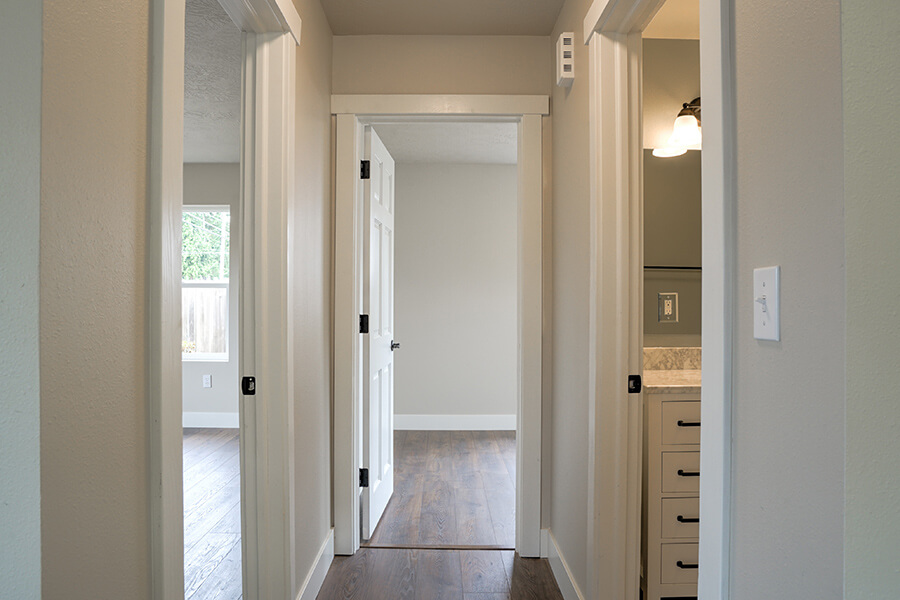 Photo of hallway in remodel showing fresh paint, white molding and hardwood floors throughout.