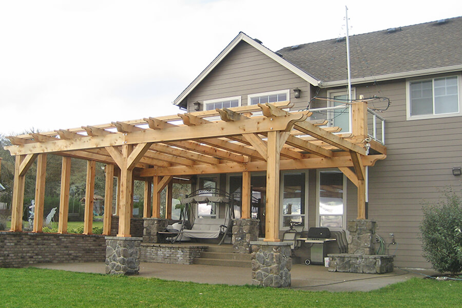 Photo of a backyard pergola addition showing the entire porch including a BBQ and a porch swing.