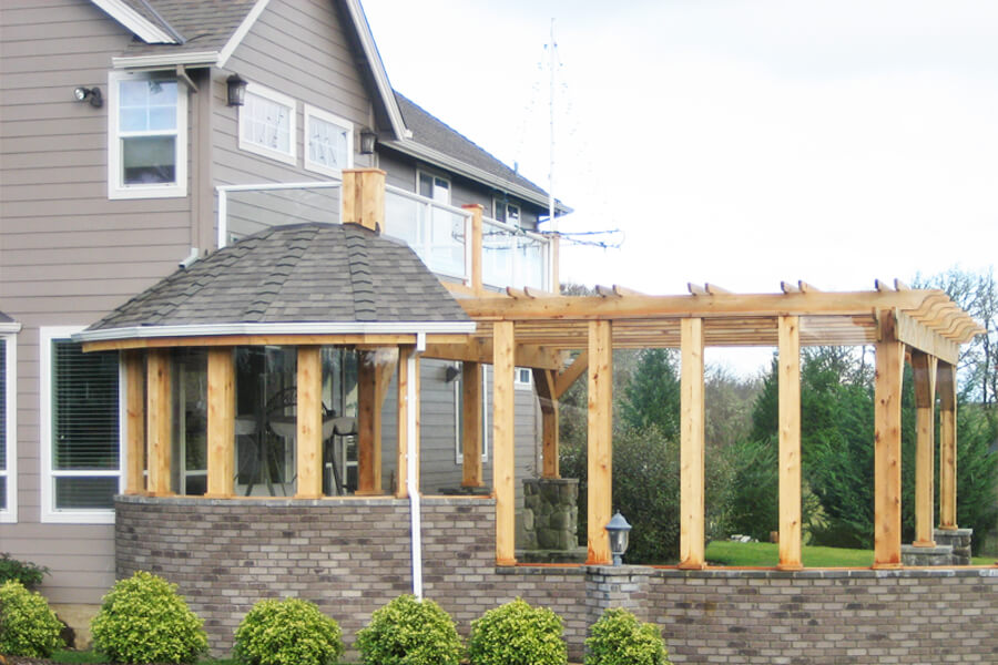 Side view photo of a wooden backyard pergola addition with weather barriers.
