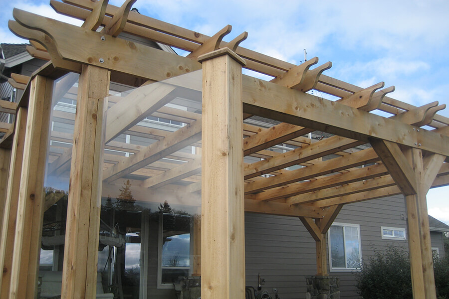 Photo of a backyard pergola addition side view showing clear weather barriers.