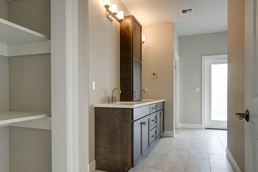 Photo of custom home bathroom with dark wood cabinets and dual sink vanity with silver hardware.