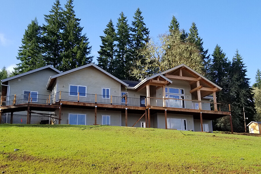 Photo of a large home with wood wrap-around porch and second story wrap-around balcony.