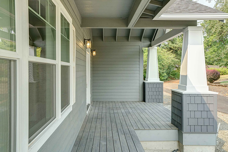 Photo of grey custom home front porch with white columns and white accents.