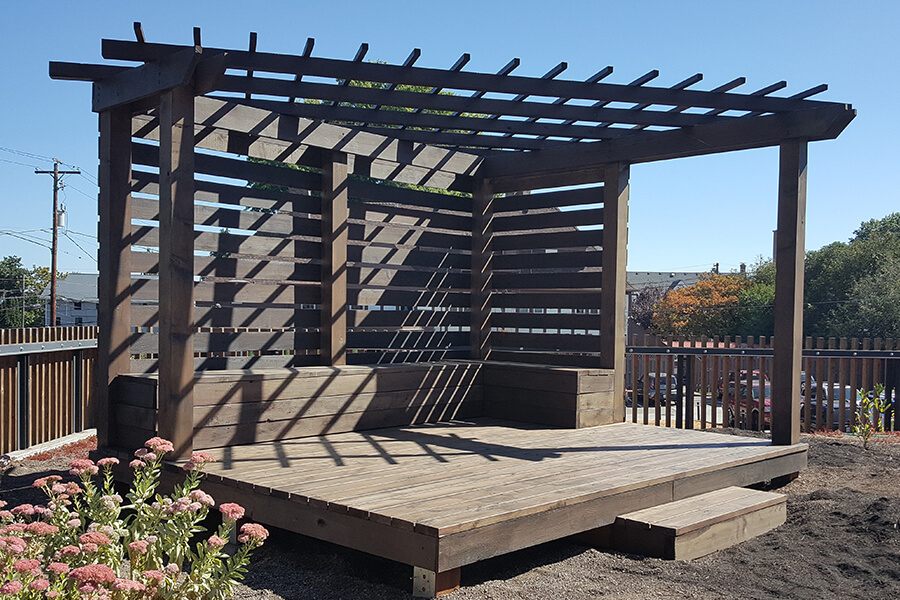 Photo of an open wooden pergola built onto a wood deck.