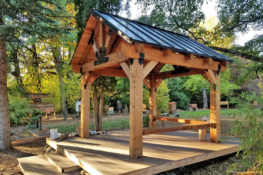 Photo of a wood pergola with a metal roof set on a wooden deck.