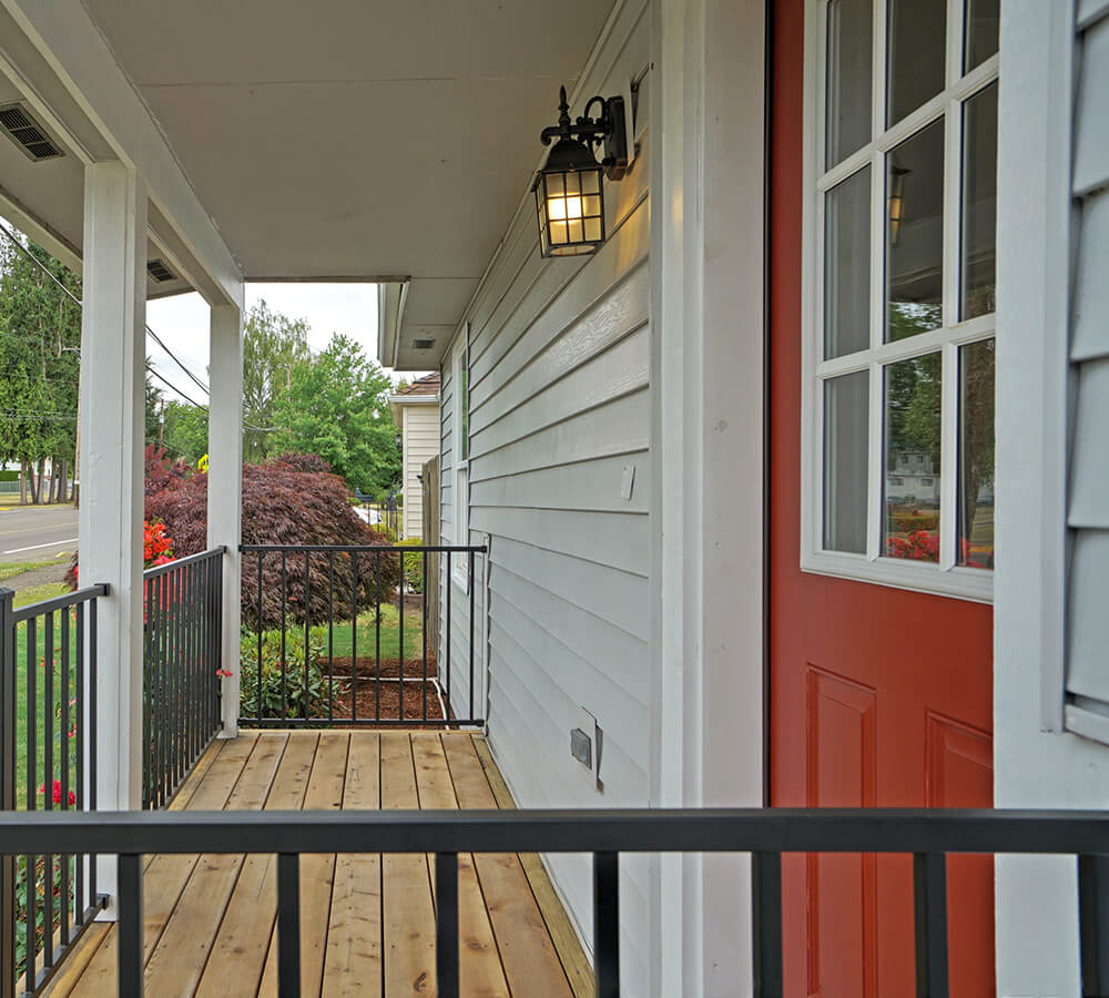 Photo of a remodeled front porch of a bungalow with a red front door.