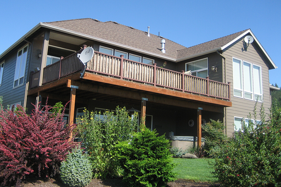 Photo of backyard of completed outdoor living additions with large porch, hot tub and balcony.