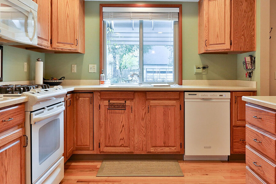 After photo of kitchen with oak cabinetry and painted green backsplash and walls.