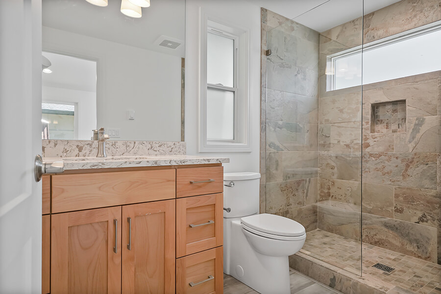Photo of bathroom showing vanity, toilet and walk-in shower with glass partition.