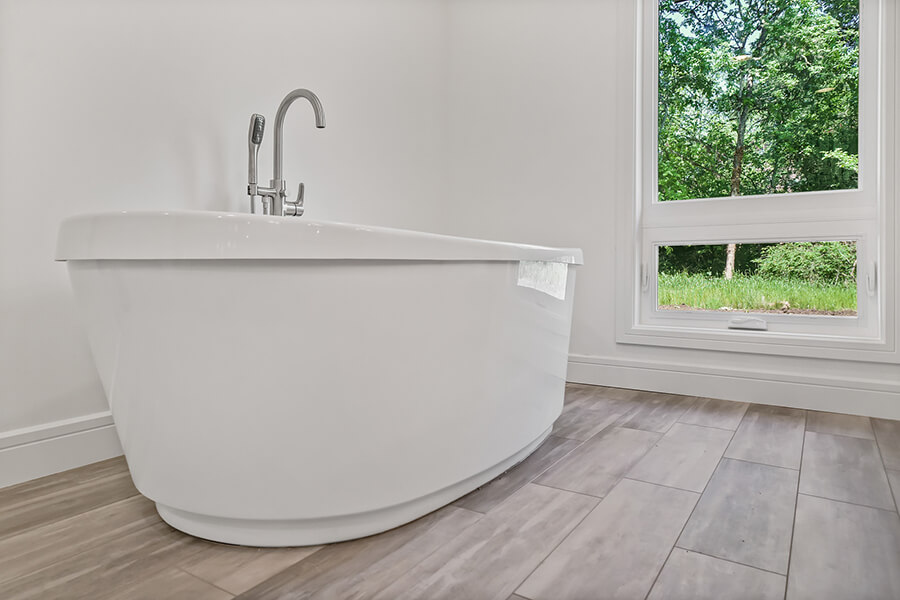 Photo of bathroom with free standing bathtub next to a large window.