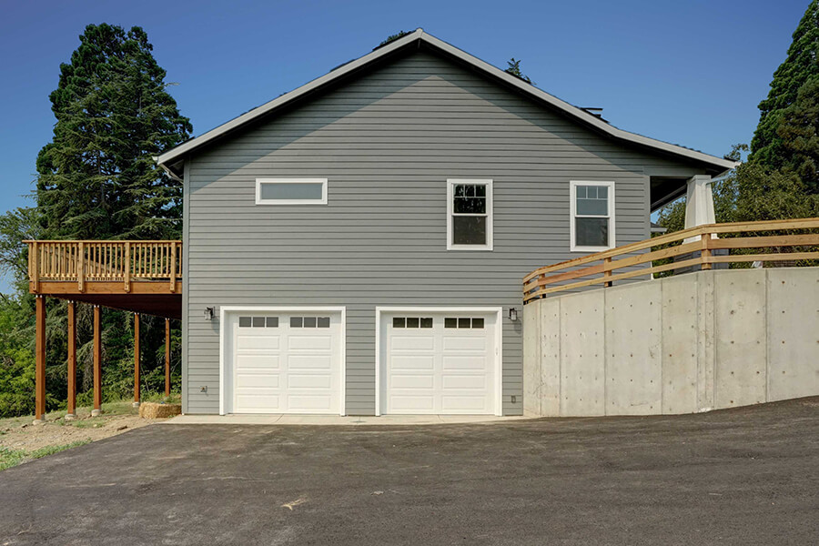 Custom home view of two garage doors with windows on the side of the house